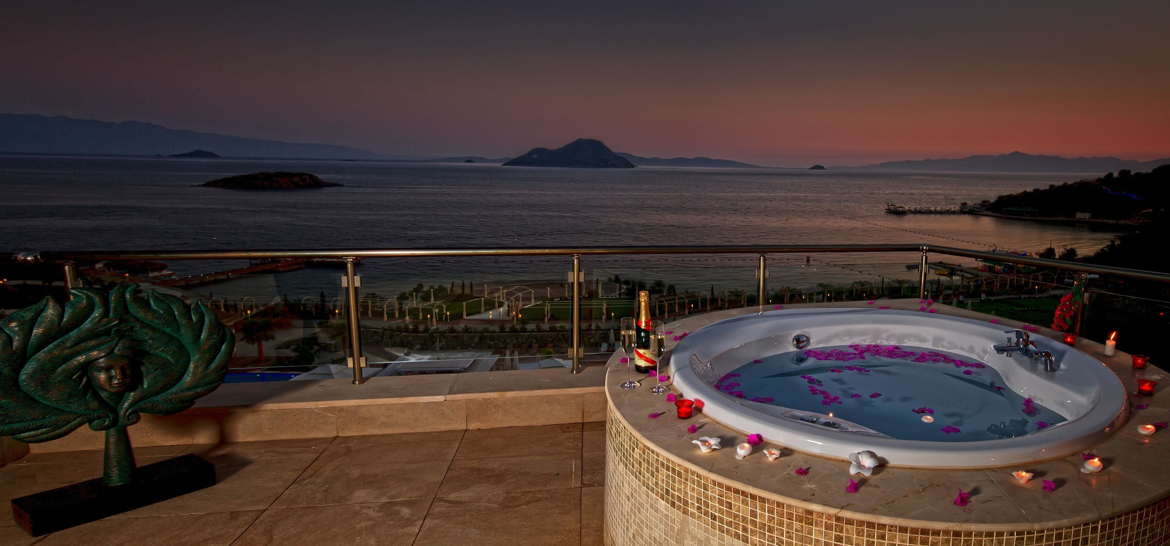 A hot tub on a balcony with a view of the sea and mountains.