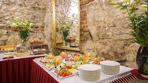 A buffet table with various food items and a mirror on a stone wall backdrop. - Hotel Wit Stwosz (Kraków)