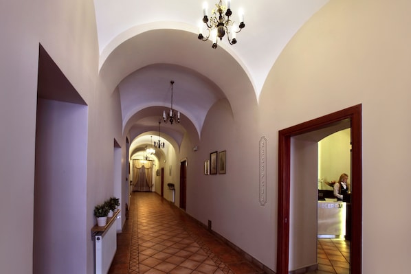 A hotel hallway with arched ceilings, a reception desk, and a chandelier.