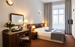 A hotel room with a bed, bedside lamps, a desk with a mirror, a chair, and a TV on the wall. - Hotel Wit Stwosz (Kraków)