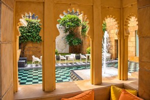 An indoor courtyard with a checkered floor, white chairs, and a fountain. - The Leela Palace Udaipur (Udaipur)