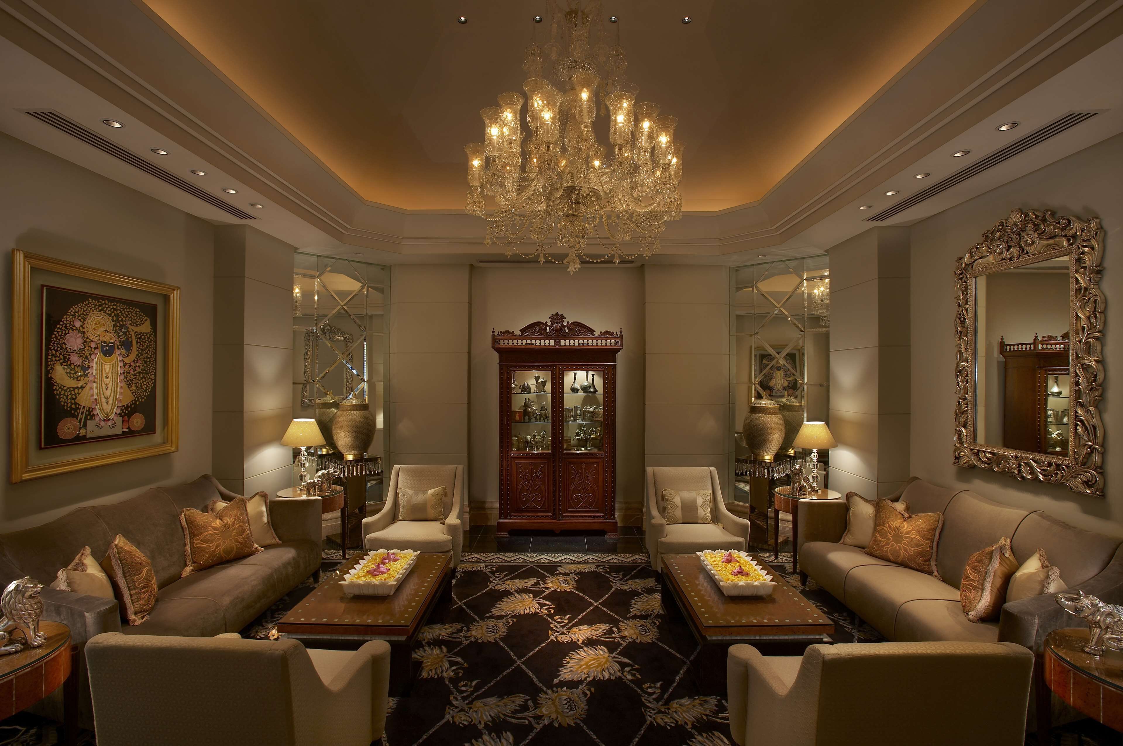 A luxurious room with a chandelier, two sofas, a coffee table, and a decorative cabinet.