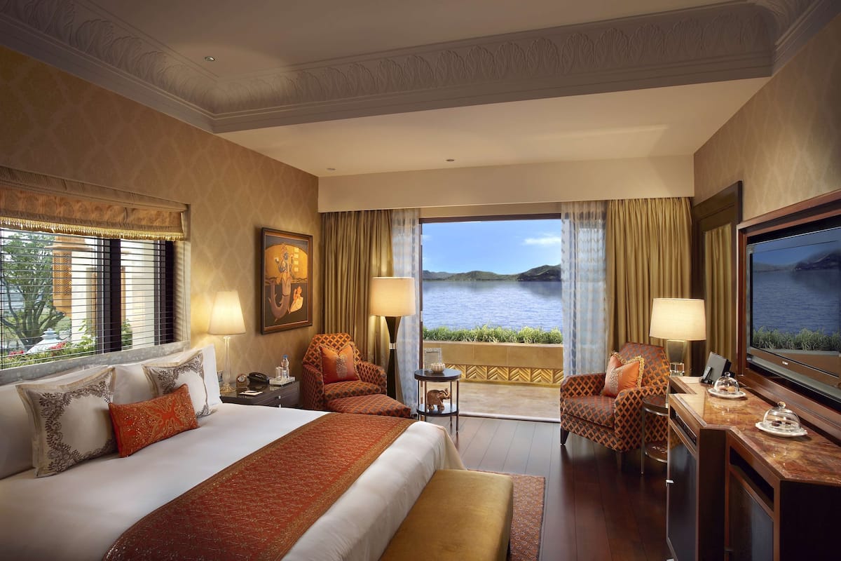 Ein Hotelzimmer mit einem großen Bett, zwei Sesseln, einem Schreibtisch mit Fernseher und einem Balkon mit Meerblick.