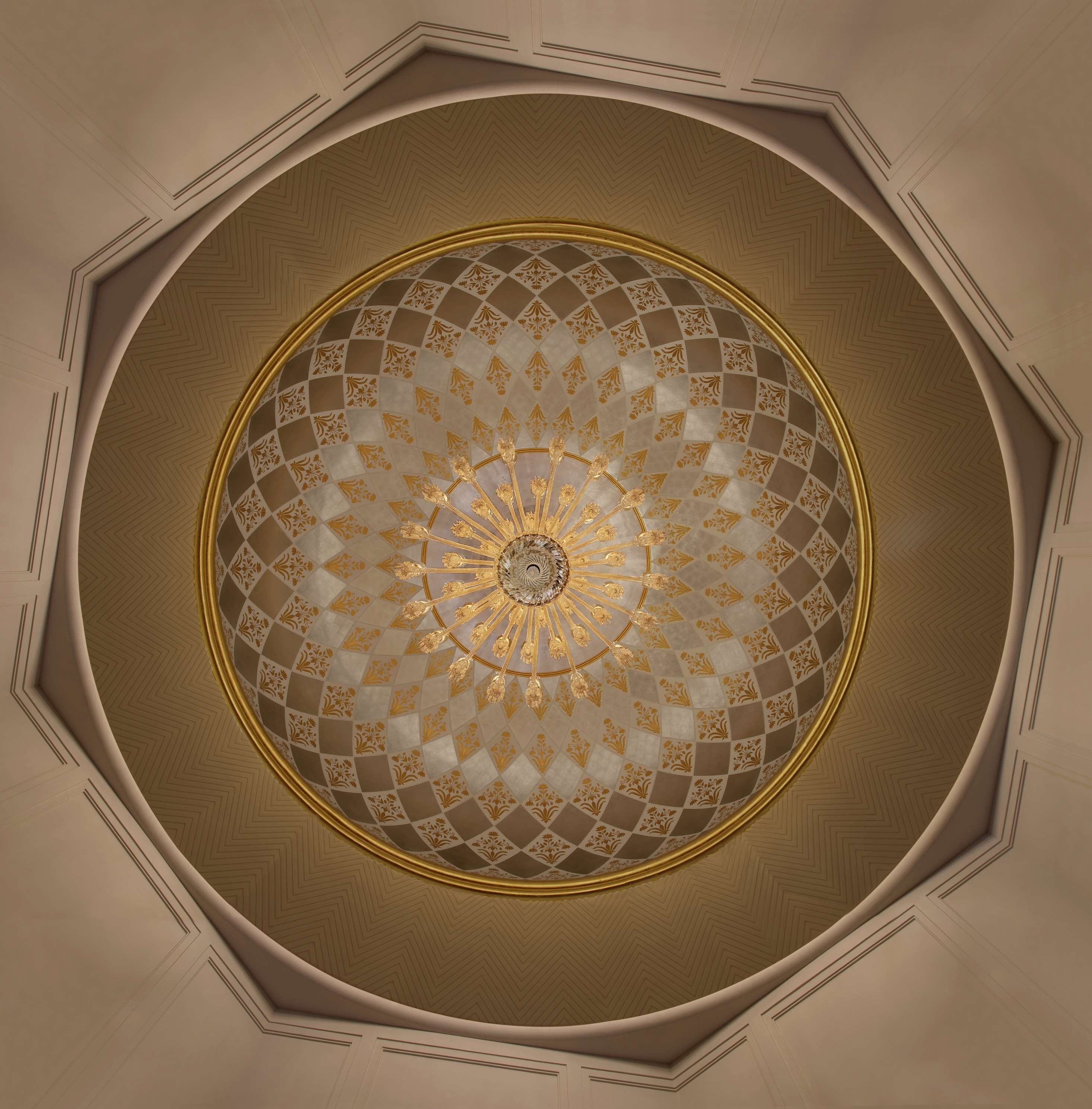A ceiling with a geometric pattern and a central chandelier.