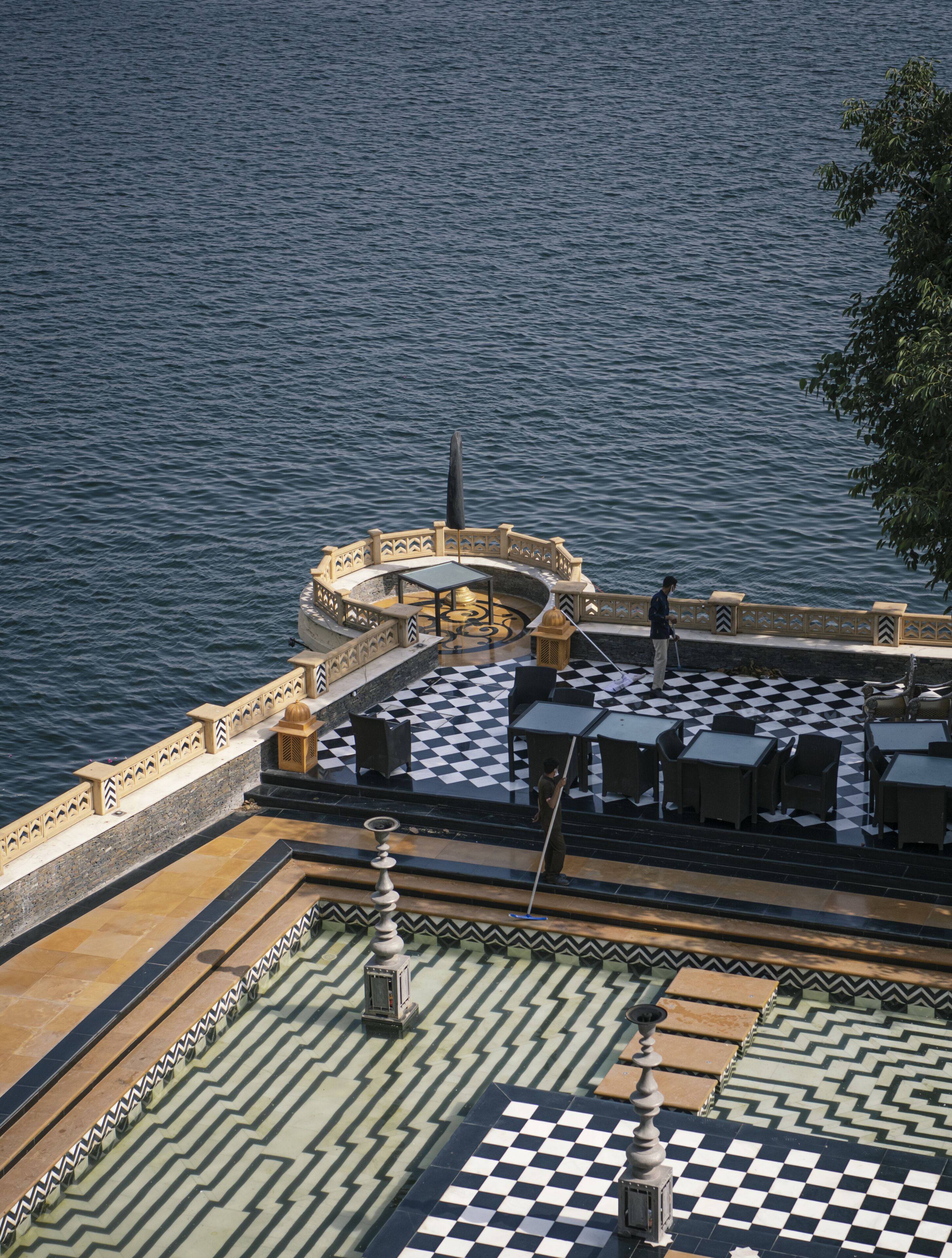 A terrace with a checkered floor, outdoor seating, and a view of the water.