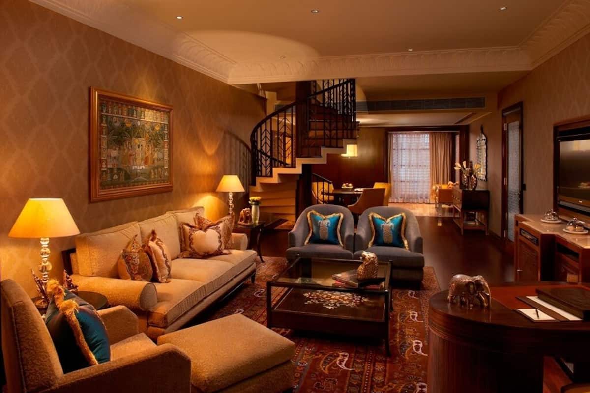 Ein geräumiges Wohnzimmer mit einer Couch, Sesseln, einem Couchtisch und einer Treppe.
