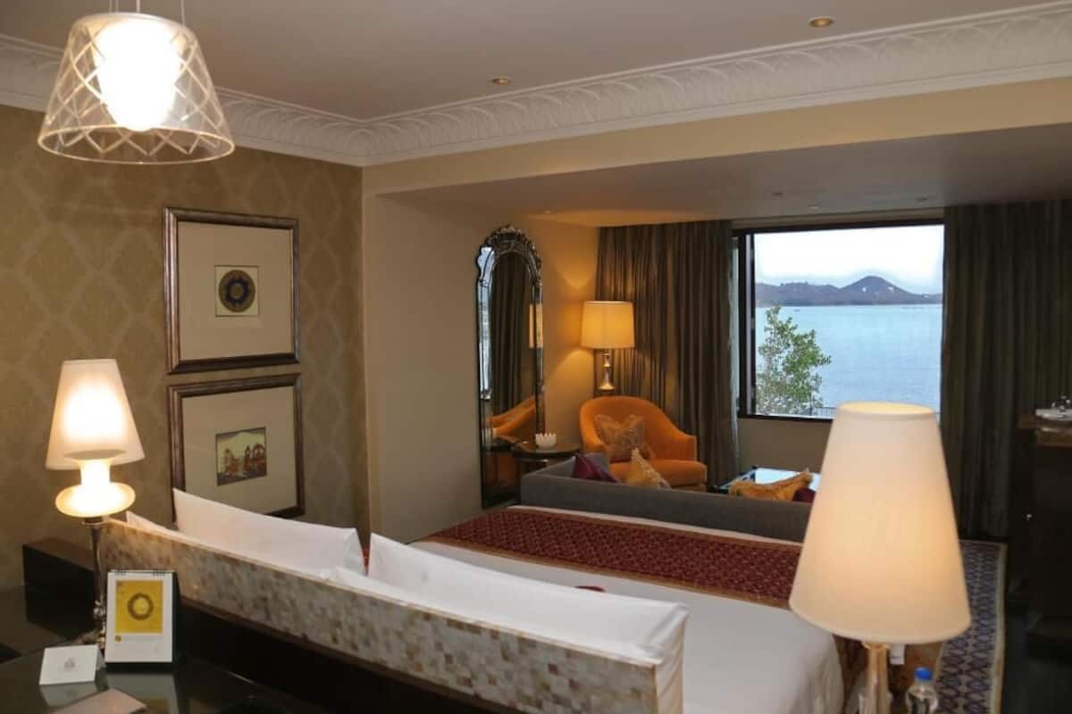 Ein Hotelzimmer mit Bett, Schreibtisch, Stuhl, Lampe und Meerblick.