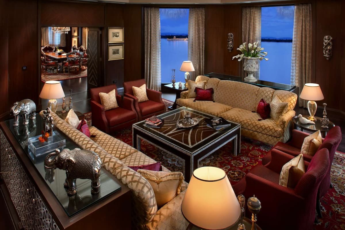 Ein luxuriöses Wohnzimmer mit einem prunkvollen Kronleuchter, bequemen Sitzmöglichkeiten und Blick auf das Wasser.