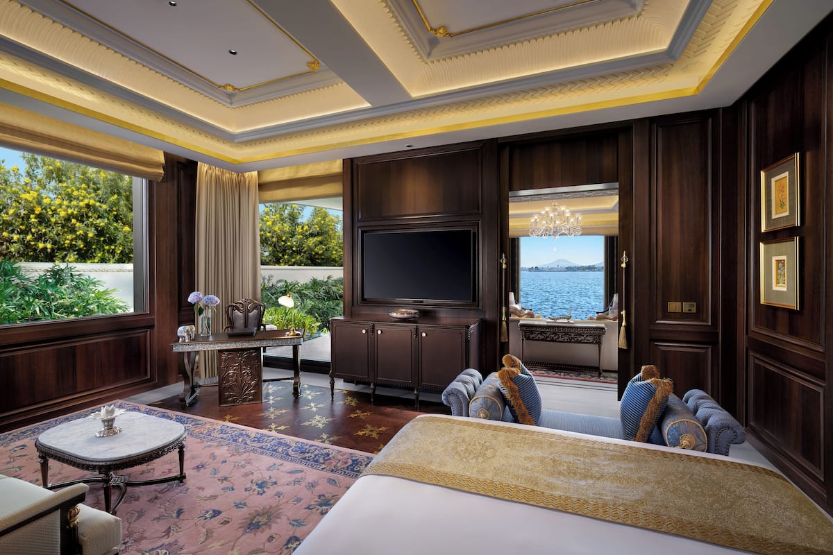 Ein luxuriöses Hotelzimmer mit einem großen Bett, einem Fernseher, einer Sitzecke und Blick ins Freie.