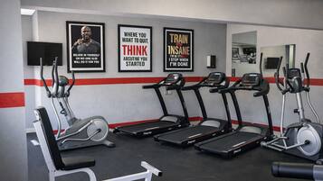 A gym with treadmills, elliptical machines, and a bench press. There are motivational posters on the wall.