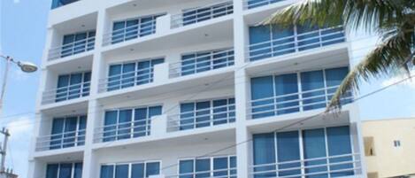 A multi-story hotel with a white facade, large windows, and a visible entrance with steps.