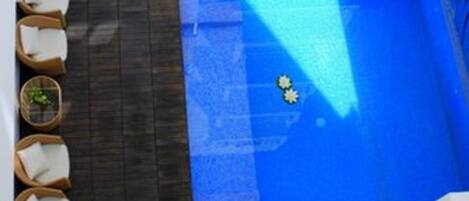 A modern outdoor pool area with a wooden deck, lounge chairs, and a small pool.