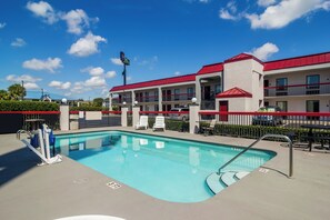 A hotel with a swimming pool, outdoor seating, and a red-roofed building. - Red Roof Inn Kingsland (Kingsland)