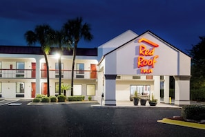 A Red Roof Inn with a two-story building, a parking lot, and palm trees.