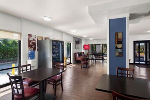 A hotel lobby with a dining area, a water dispenser, and a sign indicating free Wi-Fi availability. - Red Roof Inn Kingsland (Kingsland)