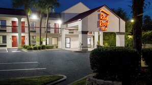 A Red Roof Inn with a two-story building, a parking lot, and a well-maintained lawn.