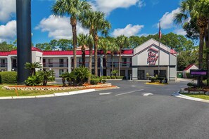 A Red Roof Inn with a red roof, palm trees, and a clear sky. - Red Roof Inn Kingsland (Kingsland)