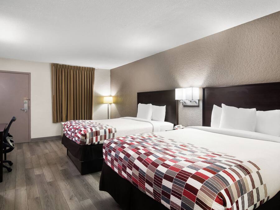 A hotel room with two beds, a desk, and a chair.