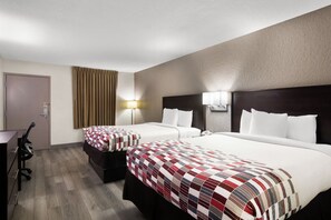 A hotel room with two beds, a desk, and a chair.