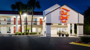 A Red Roof Inn with a two-story building, a parking lot, and palm trees.