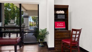 A room with a dining table, chairs, a potted plant, a wooden cabinet, and a red chair.