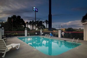 Una piscina con sillas de descanso y un cartel de Best Western Plus.