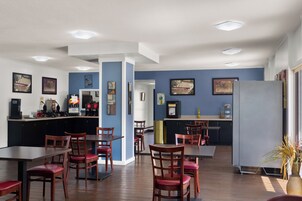 Un comedor moderno con mesas y sillas de madera, una barra de cocina y paredes azules.