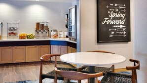 A modern kitchen with a round dining table and wicker chairs, equipped with a coffee machine and various food dispensers. - Fairfield Inn & Suites by Marriott Albany (Albany)