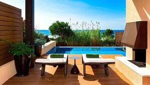 Un espace aménagé au bord de la piscine, avec deux chaises longues, un barbecue et une vue sur l’océan.