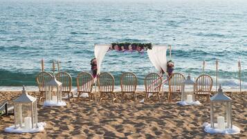 Romantic beach wedding setup with a beautiful arch, floral decorations, and a serene ocean view.