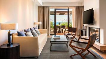Een moderne hotelkamer met een bank, salontafel, stoelen, een televisie en een open haard.