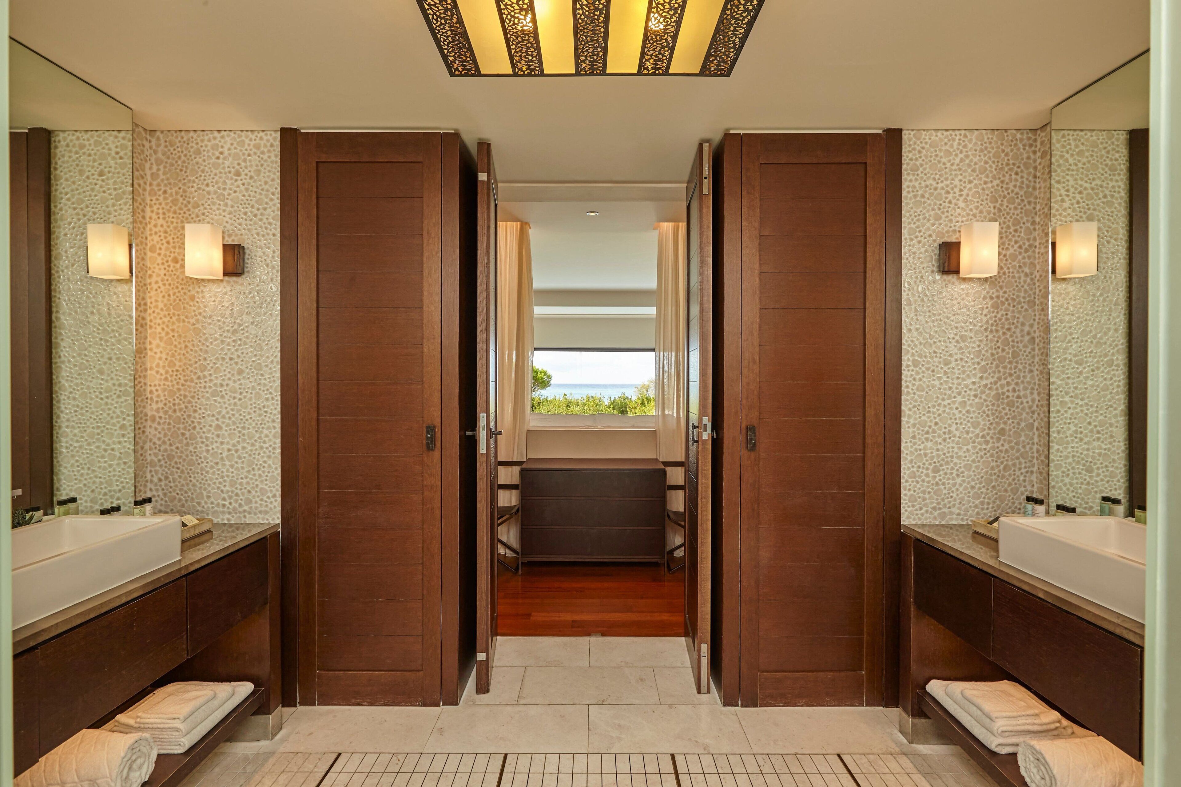 A modern bathroom with two sinks, a walk-in shower, and a view of the outdoors.