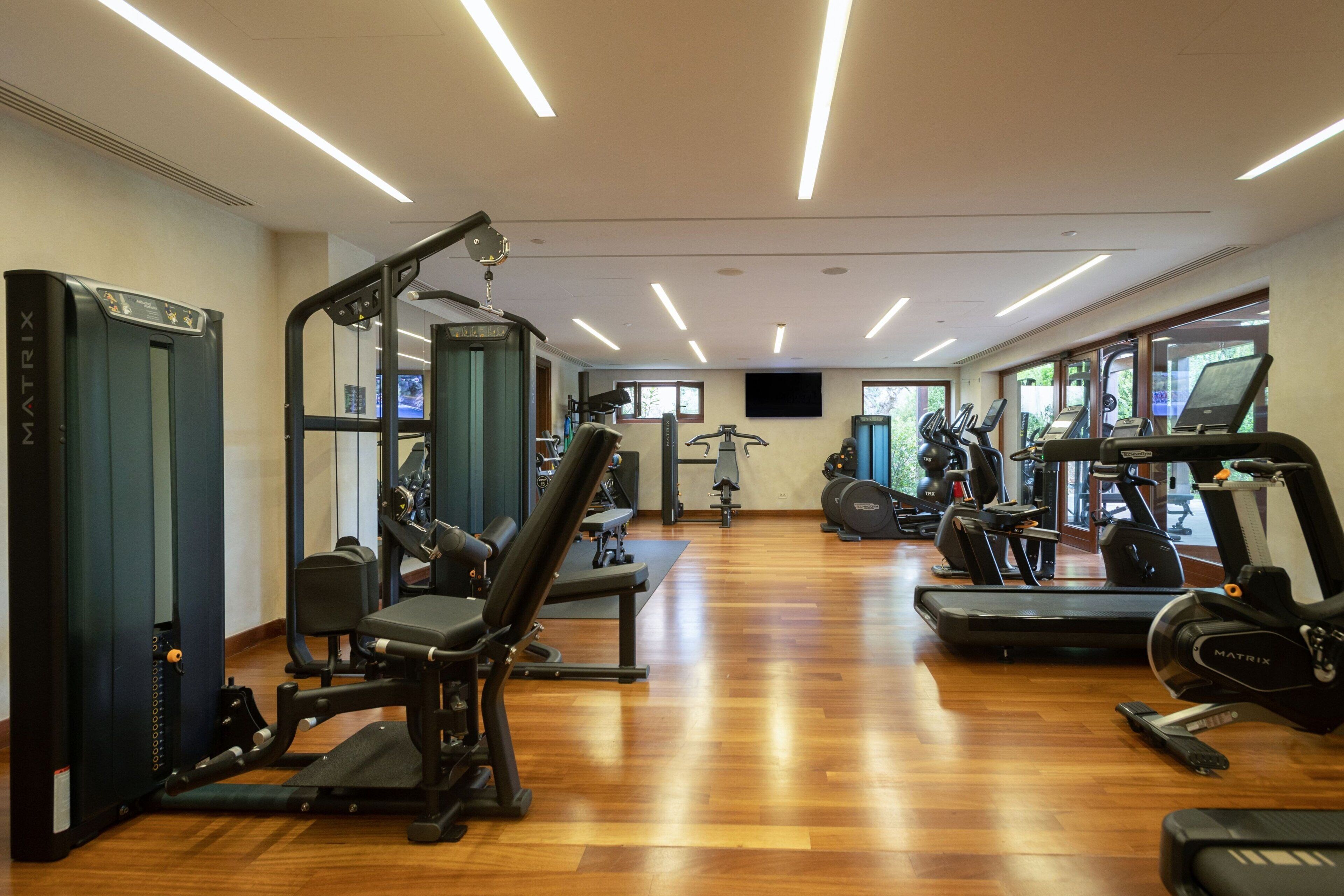 A gym with various exercise equipment, including treadmills, elliptical machines, and weight machines.