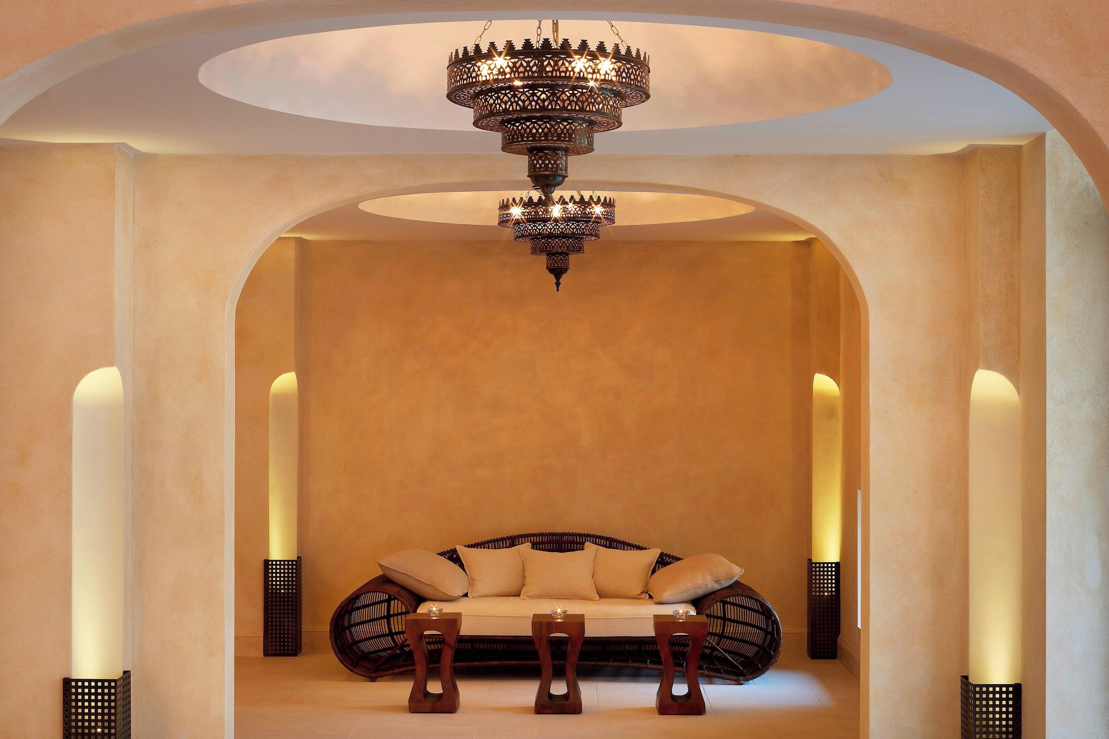 A cozy seating area with a sofa and two side tables, a decorative chandelier, and wall sconces.