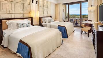 Quarto de hotel com duas camas, varanda com vista, televisão e escrivaninha.