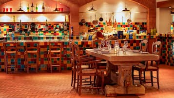 Un restaurante con un colorido salpicadero de azulejos, sillas de madera y una mesa central con copas de vino.