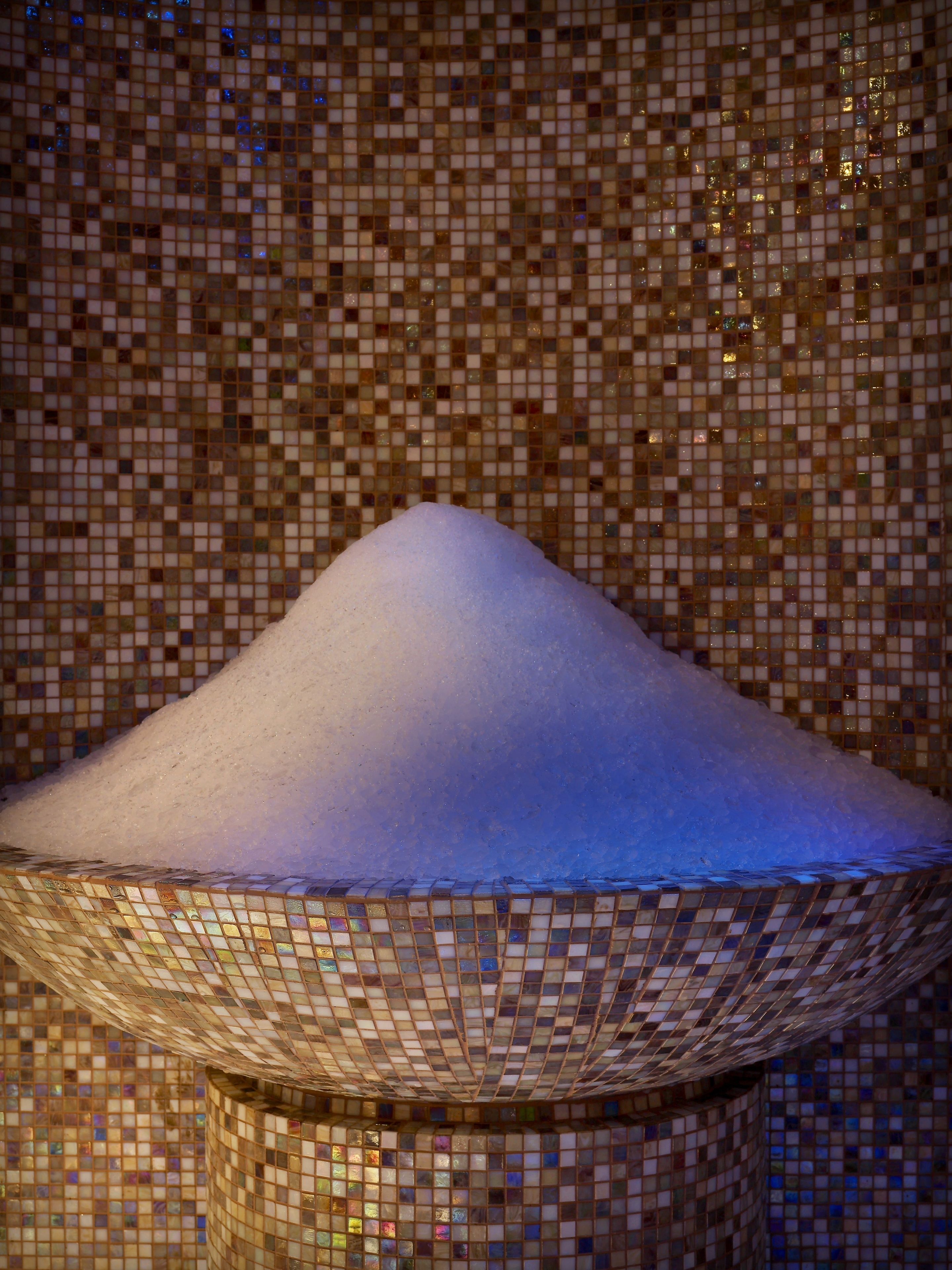 A snow-covered conical structure with a mosaic tile background.