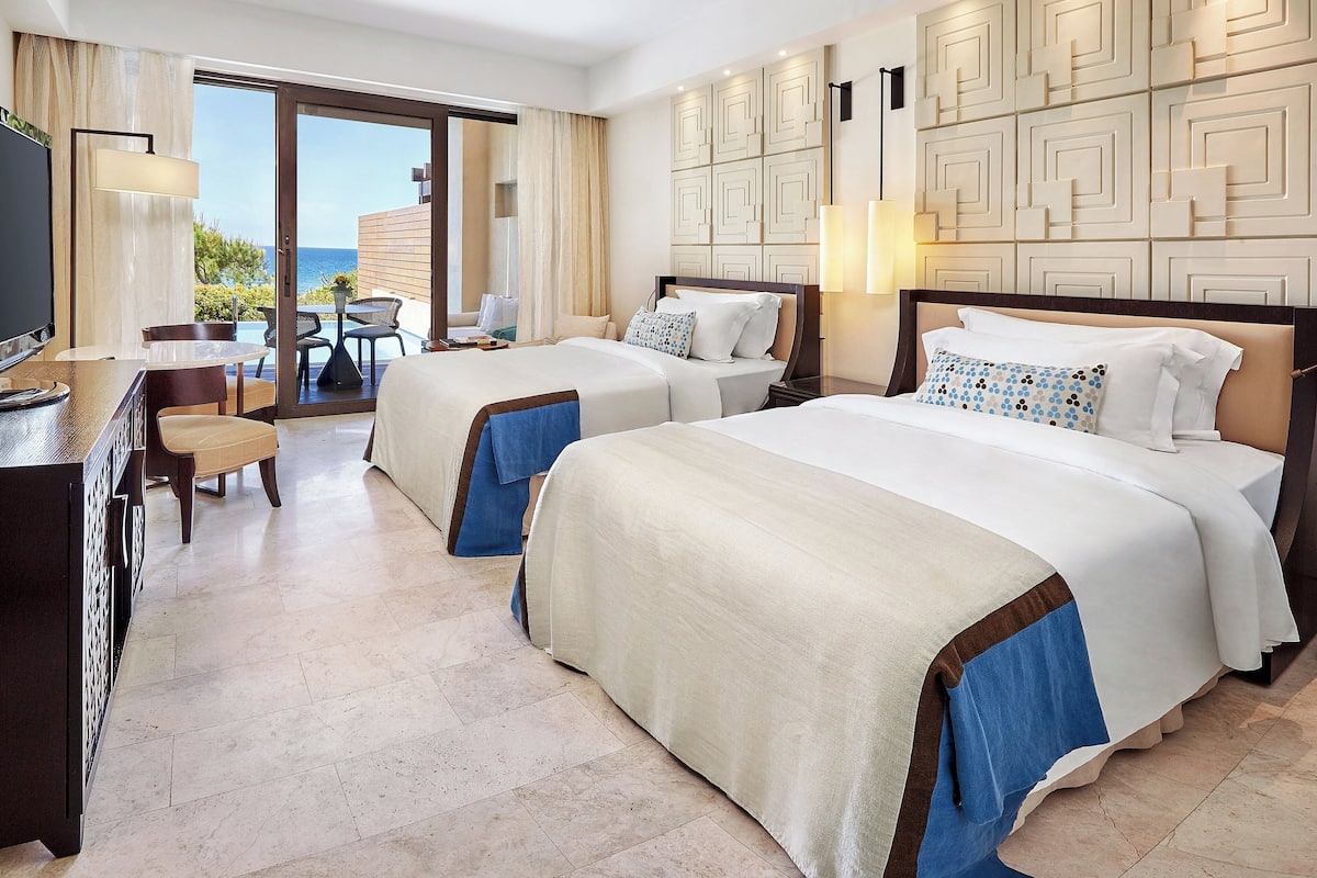 A hotel room with two beds, a desk, and a chair.