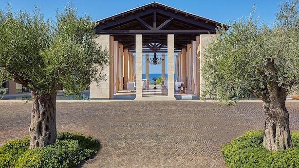 Un pavillon abrité, doté d’un sol carrelé, entouré d’arbres et surplombé d’un ciel bleu azur.