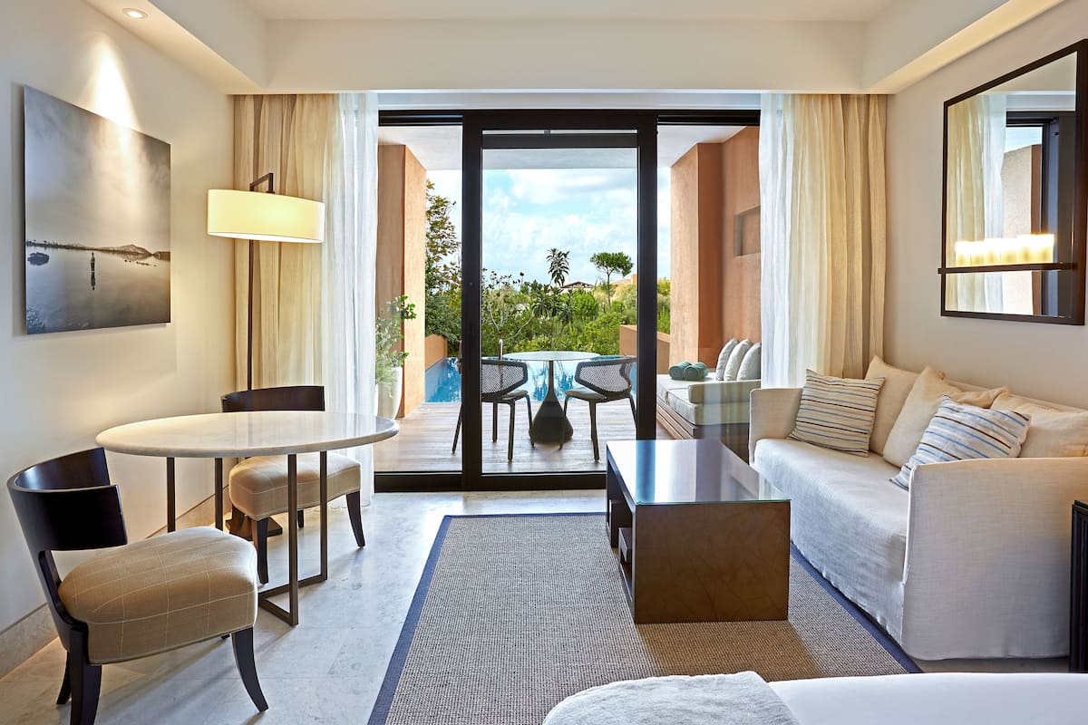 A hotel room with a balcony, a dining area, a sofa, and a bed.