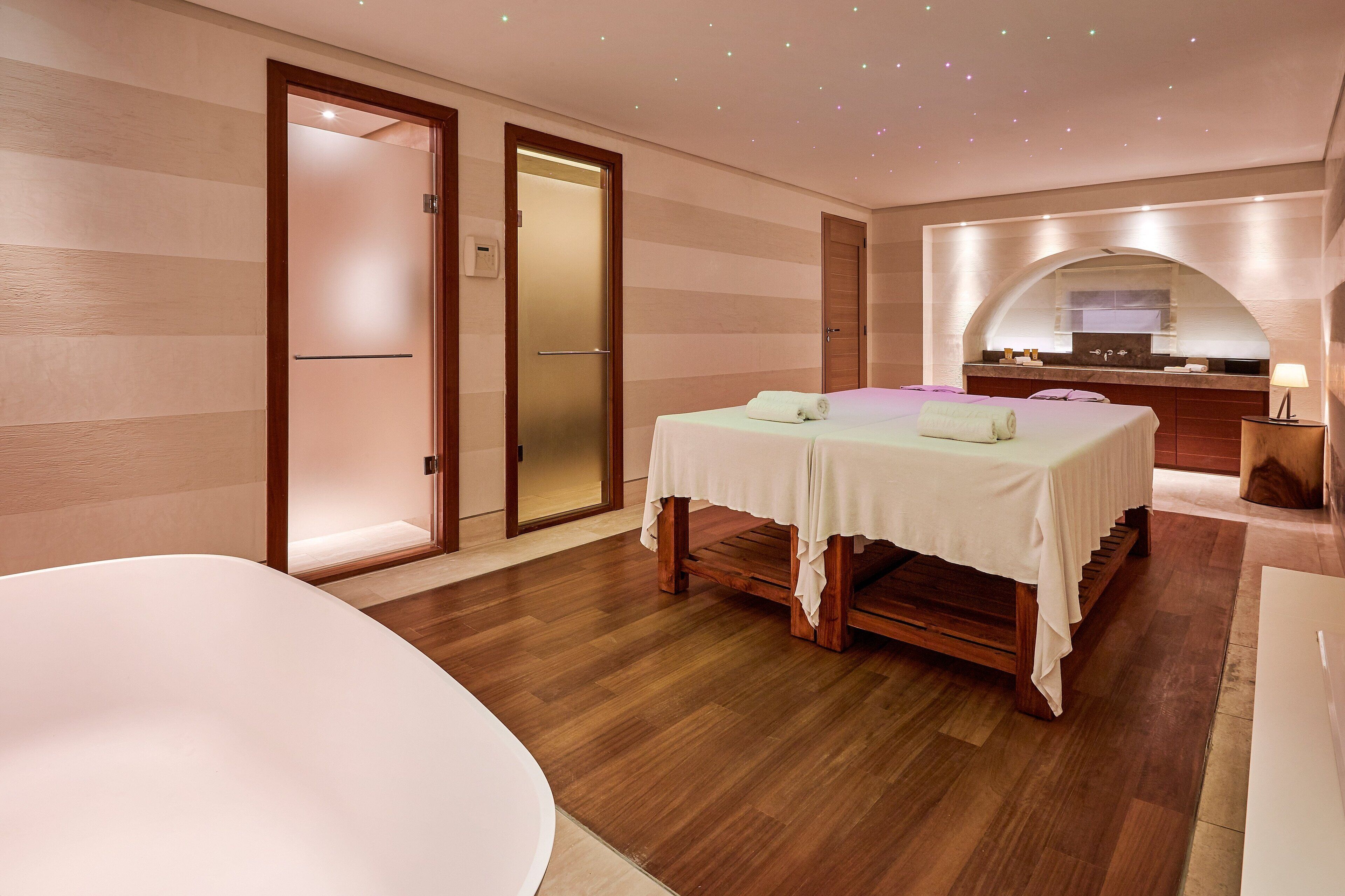 A hotel room with a large bed, a separate seating area, a small kitchen, and a bathroom.