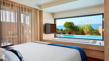 A bedroom with a large bed, a window with a view of the sea, and a bathtub.
