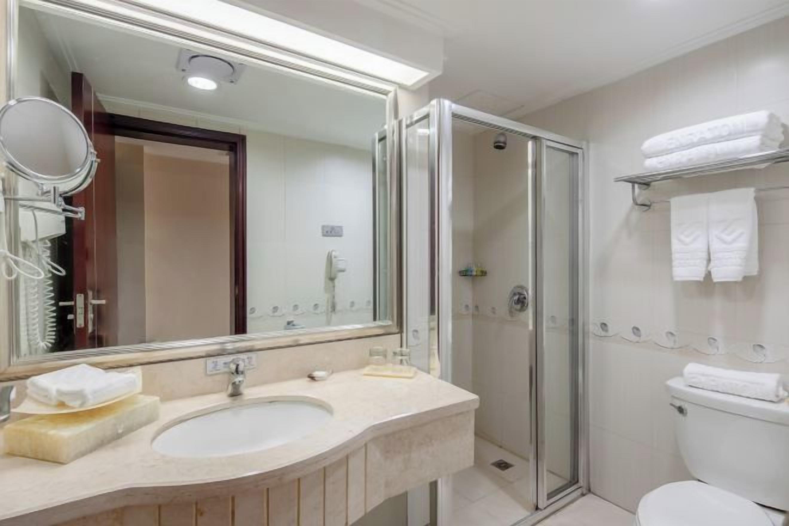A bathroom with a double sink, a glass shower enclosure, and a toilet.