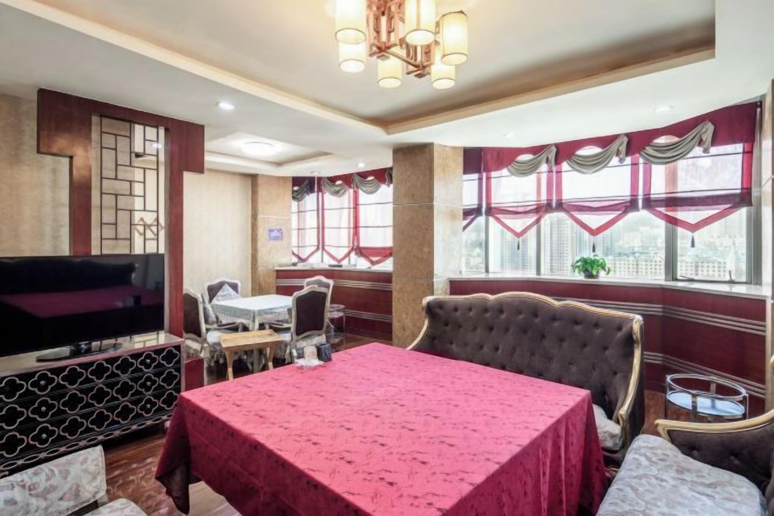 A hotel room with a large bed, a dining table, a TV, and a window with curtains.