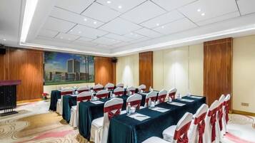 Un salón de conferencias con una mesa larga, sillas y un atril.