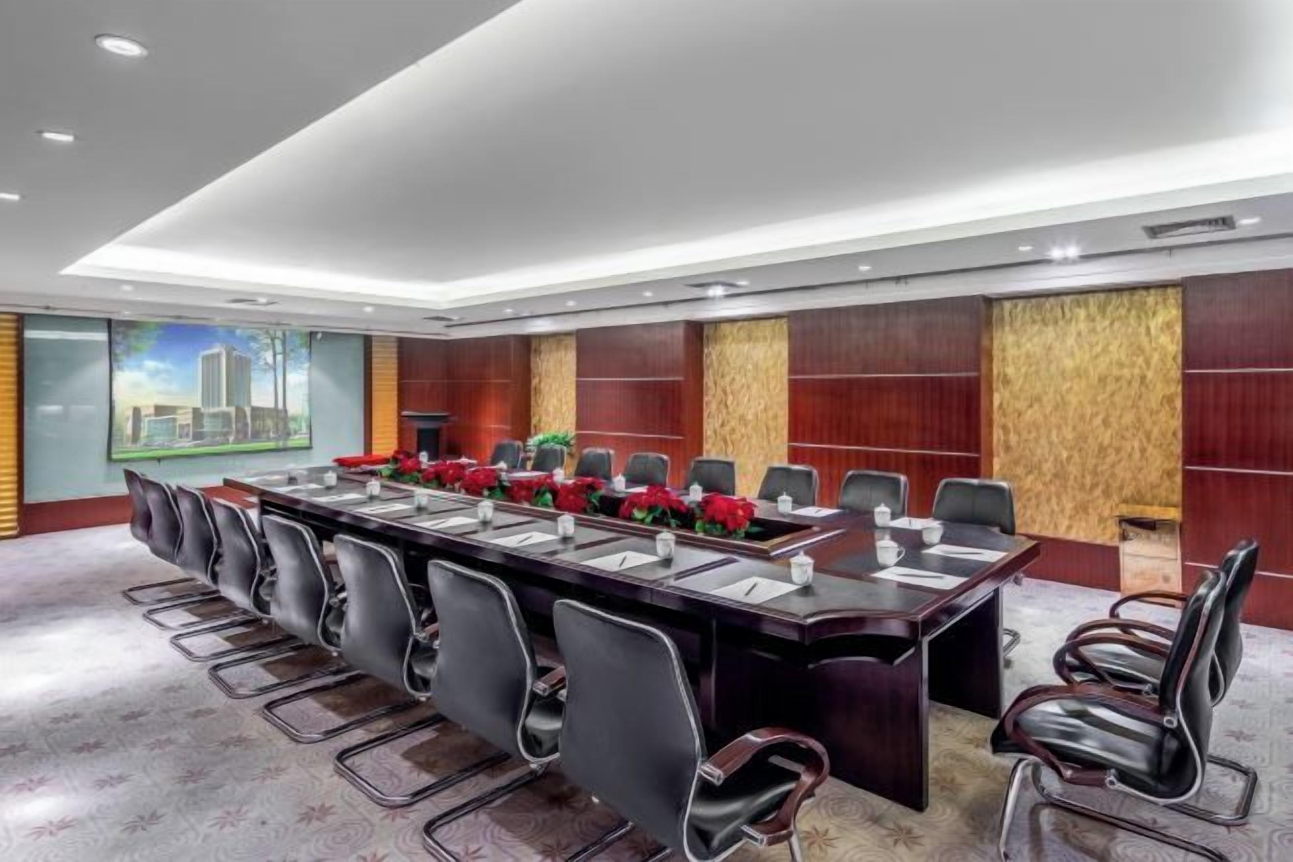 Un salón de conferencias con una larga mesa, varias sillas y vistas a la ciudad.