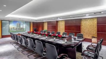 Un salón de conferencias con una larga mesa, varias sillas y vistas a la ciudad.