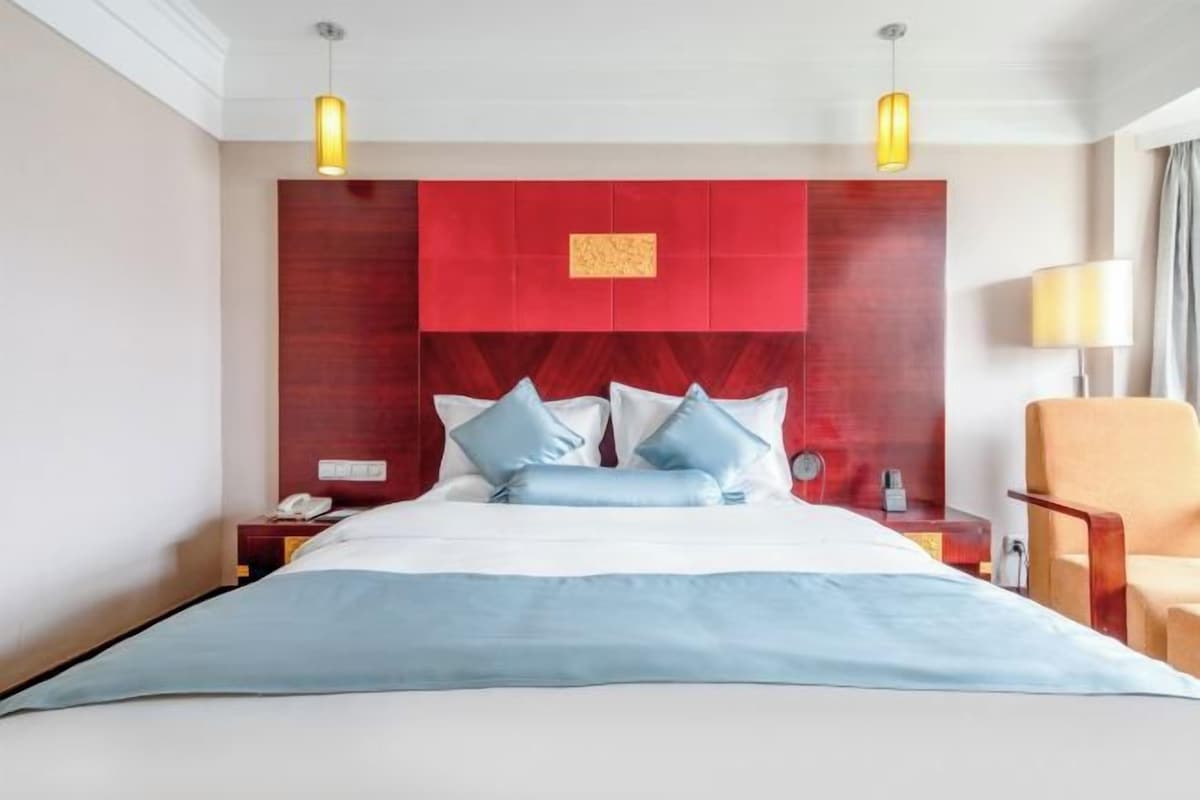 Una habitación de hotel con cama, mesitas de noche, una silla y una lámpara.