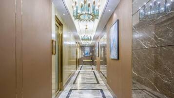 Un pasillo de hotel con piso de mármol, una araña y cuadros en las paredes.
