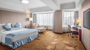 Quarto de hotel com uma cama grande, uma mesa, uma cadeira e uma televisão.